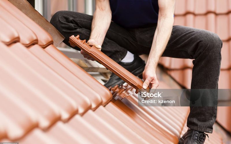 Roofing - construction worker standing on a roof covering it with tiles