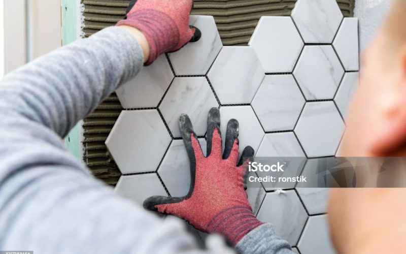 tiling - man laying marble texture hexagon tiles on the wall
