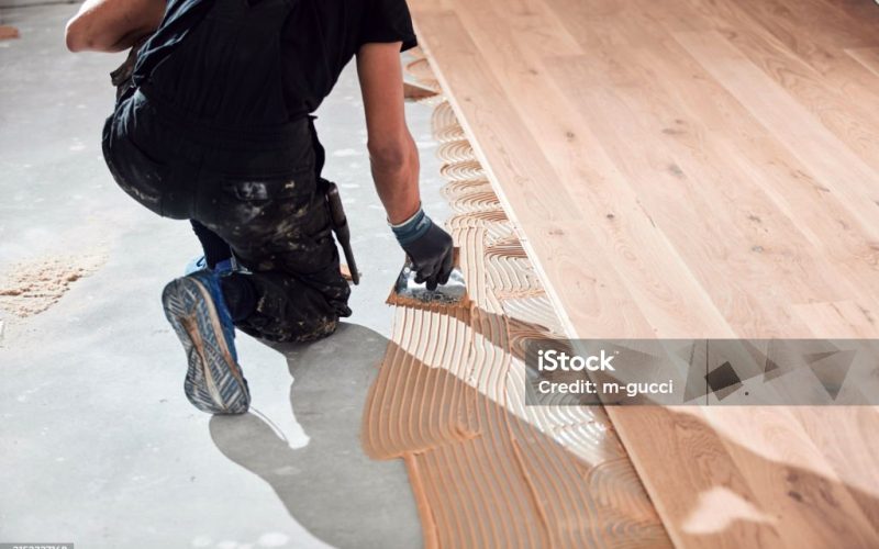 Professional handyman installing laminate flooring in a new apartment.